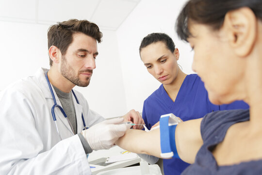 male doctor preparing syringe for female patients arm