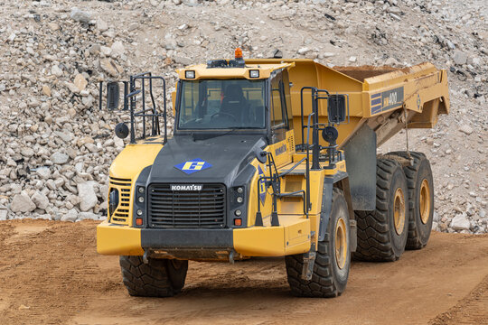Luxembourg City, Luxembourg - August 3rd 2019 : View on a yellow articulated dump truck Komatsu HM400 on a construction site with a pile of earth in the background.
