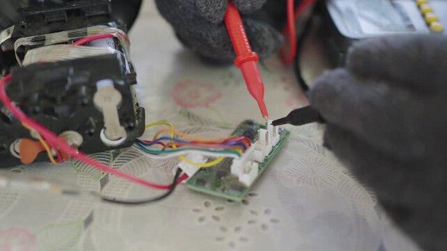 Close-up, hands of woman are using a multimeter to check the vacuum cleaner's circuitry.