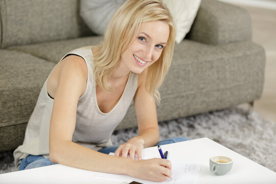 smiling girl looking at camera while making notes