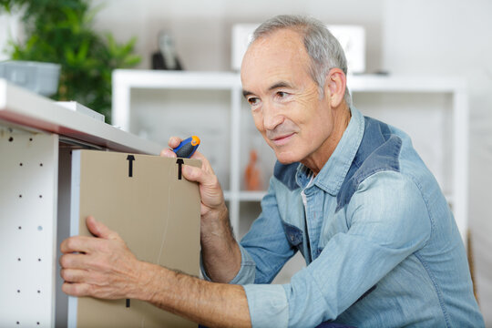 mature man assembling kitchen cupboard