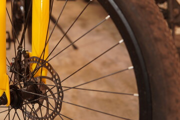 Close up of a bicycle disc brake system and stainless steel spokes on a yellow bike