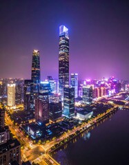 Fototapeta premium An aerial view showcases the dazzling nighttime cityscape of Shenzhen, China, with towering skyscrapers illuminated against a deep blue sky and reflecting in the river below.