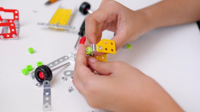Close up of child hands assembling 3D printed robot model on table. Concept of STEM education, robotics learning, creativity, and technology development