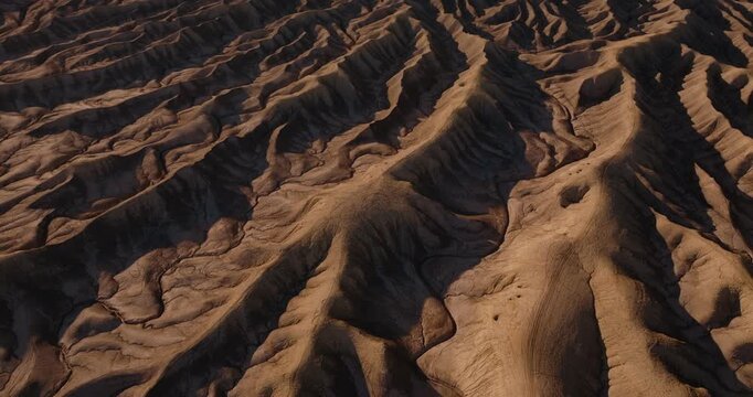 Aerial patterns of winding desert ridges and eroded badlands near Factory Butte Utah, tilt up following winding features