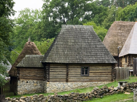 Traditional wooden log cottage with a high wooden shingle roof and stone foundation at the Astra Museum in Sibiu, Romania.