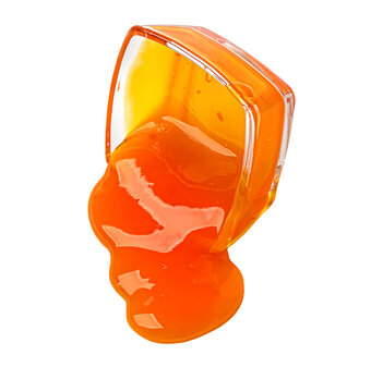 Orange liquid pouring from transparent cup splashing