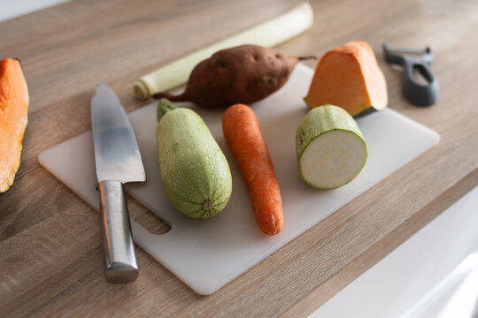 Fresh vegetables on cutting board with zucchini carrot potato and pumpkin on kitchen table