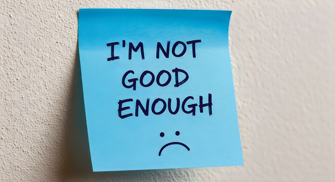 Blue sticky note with "I'm not good enough" and a sad face drawn in marker on a textured wall