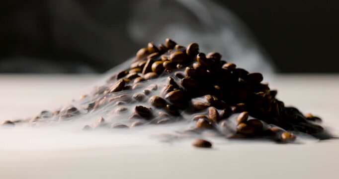 A pile of roasted coffee beans emits gentle steam, creating a rich, aromatic atmosphere against a dark background. Shallow depth of field highlights texture and warmth