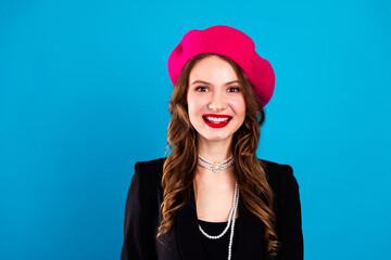 Naklejka premium Young chic woman in pink beret smiles against blue background wearing black blazer pearls and red lipstick for fashion lifestyle advertising