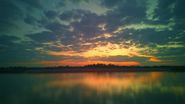 An aerial hyperlapse captures a dramatic sunset over the Mekong River, where golden light spreads across riverside farmlands and rural landscapes. Dramatic Evening Skies Above Mekong Riverside