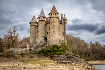 Naklejka premium A dramatic photograph of the Chateau de Val, a perfectly preserved medieval castle perched on a rocky promontory above the shore of the Bort-les-Orgues reservoir in the Cantal department of Auvergne. 