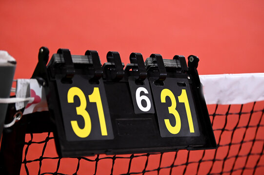 A manual flip-style scoreboard hanging on a net