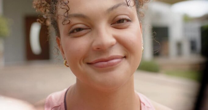 African American woman 20s leaning into camera as focusing engaging laughing in pink tank on porch