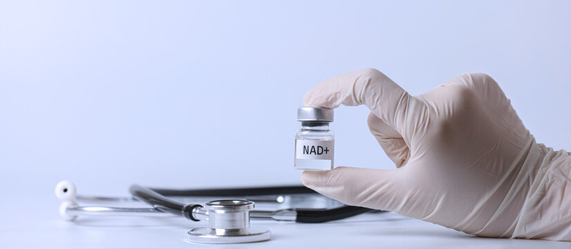 Doctor hand in medical glove holds nad+ vial expressing hopeful longevity treatment concept near stethoscope in hospital clinic