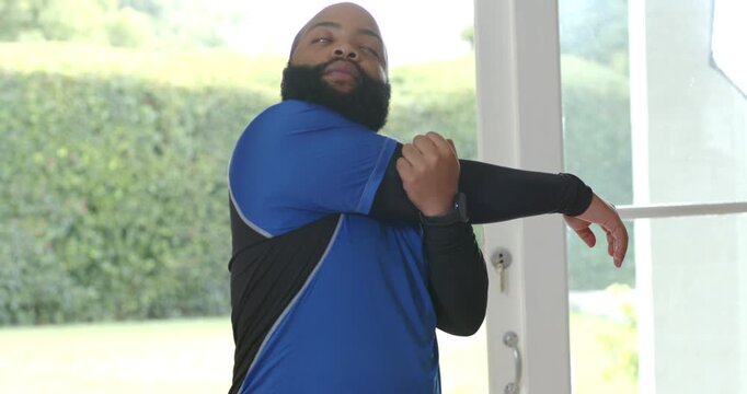 Vertical video: Entering man in top with compression sleeve pulling arm across at door warming up