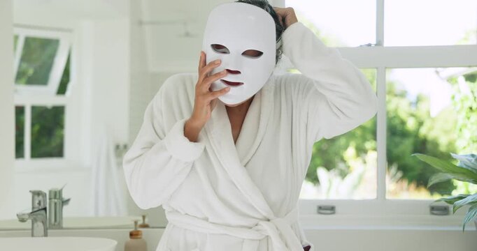 African American woman inspecting, donning mask at sink in bathrobe, tapping phone starting therapy