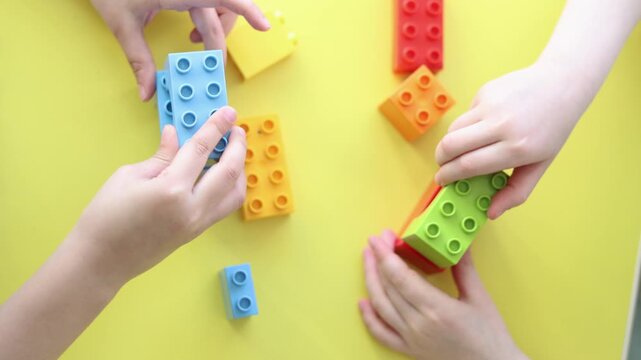 The hands of two kids are shown working together with a construction set, connecting vibrant blocks and creating fun designs. Their focus and collaboration highlight the joy of creative play.