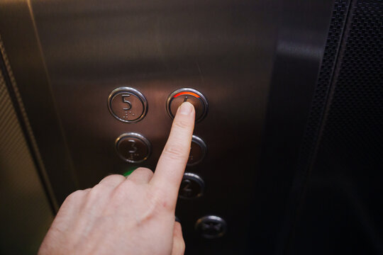 Hand presses elevator button to go to upper floor