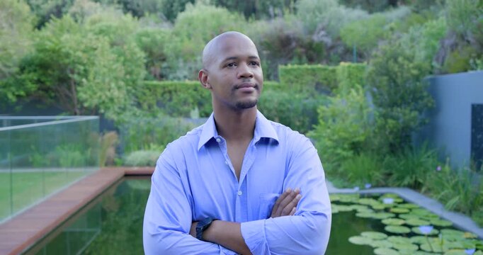 Vertical video: Camera is moving closer, and man is glancing around and smiling by garden pond
