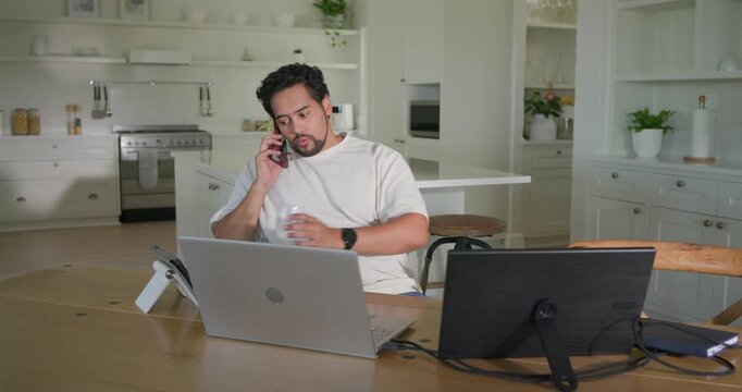 Man taking work call leaning back ending call checking phone refocusing laptop or monitor in kitchen
