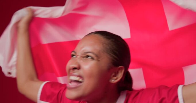 African American female in red jersey cheering for goal, shouting and waving red-white flag on set