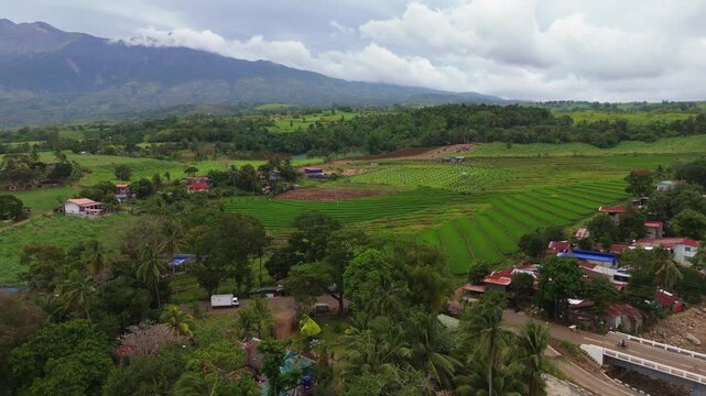 Aerial view of Mount Canlaon volcano towering over lush green agricultural fields and rural landscapes in Canlaon City, Negros Oriental, Philippines. Stunning volcanic scenery