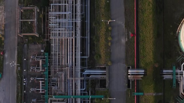Aerial view of industrial pipes and storage tanks creating a complex network against the green and grey landscape, Setubal, Portugal.