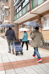 People walking on a wet sidewalk carrying umbrellas during a rainy day in the city