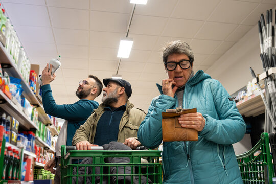 Family comparing products and checking wallet for budget in a supermarket aisle