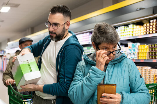 Two customers browsing and selecting items from refrigerated shelves in a grocery store