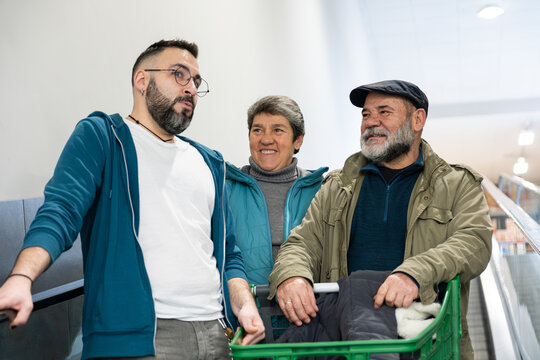 Multigenerational family members shopping together, smiling and riding an escalator in a store