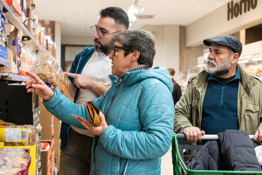 Group of people choosing products from shelves, shopping in a grocery store