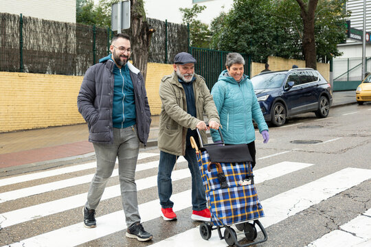 Family walking together on a crosswalk, smiling and enjoying the urban street