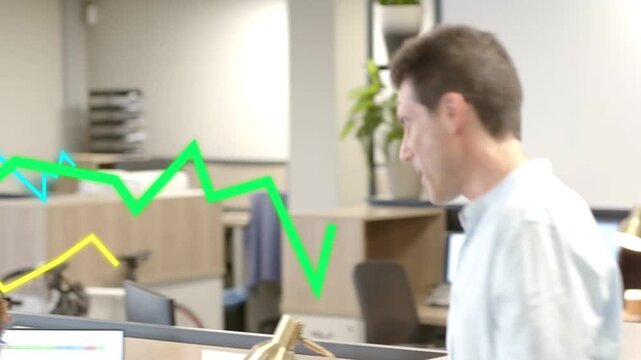 Man entering with papers starting report review, woman pointing at monitor, graph overlay on screen