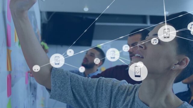 Woman reaching and placing sticky notes, team mapping product plan while icons spreading over wall