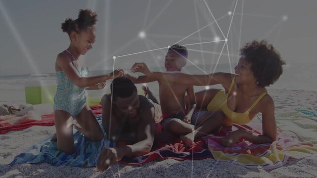 Family playing on beach, kids tugging dad's hair causing laughter for ads with faint node overlay