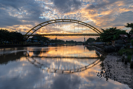 Dramatic Sunrise Reflection of the Yellow Arch Siak Bridge Over the Siak River in Pekanbaru