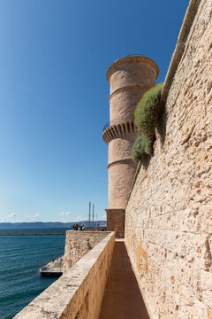 La tour du fanal du fort Saint-Jean vue du chemin de ronde sur le rempart sud, mer M&eacute;diterran&eacute;e &agrave; gauche de l'image, touristes en bas de la tour, grand ciel bleu, Marseille, entr&eacute;e du Vieux-Port