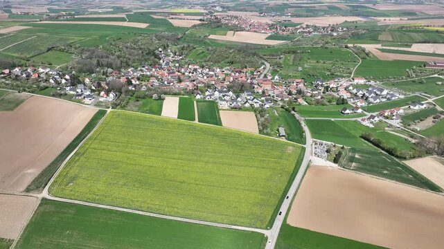 Aerial view of agricultural land showcasing a patchwork of vibrant fields, interspersed with the quaint villages, Wintzenheim-Kochersberg, Grand Est, France.