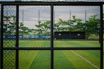 Black wire fence surrounding mini soccer field with green synthetic turf © BI4S