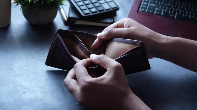 man counting expenses and showing an empty money wallet on table with calculator business accountant