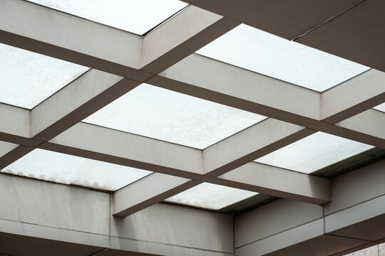 Modern geometric skylight ceiling architectural structure with metal beams and frosted glass.
