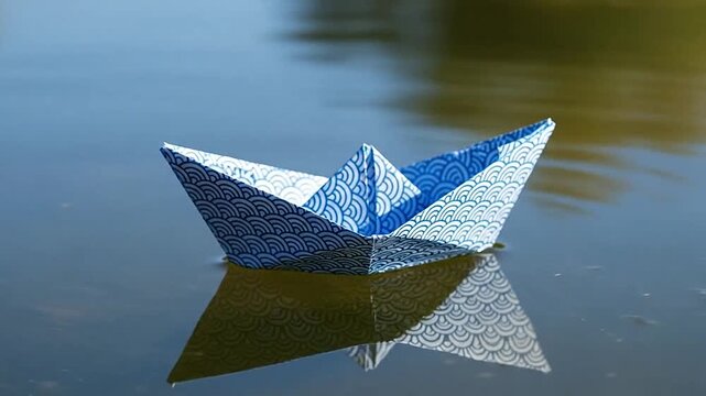 A small, folded paper boat floats peacefully on the surface of calm, blue water