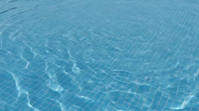 Clear blue water ripples gently in a tiled pool, creating a refreshing and inviting scene