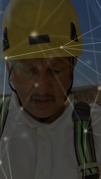 Vertical video: Site worker checking harness as camera zooming out, network mapping safety