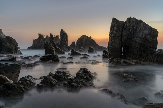 Eye-Level View of Jagged Rock Formations and Ethereal Silky Water at Gigi Hiu Beach During Sunset