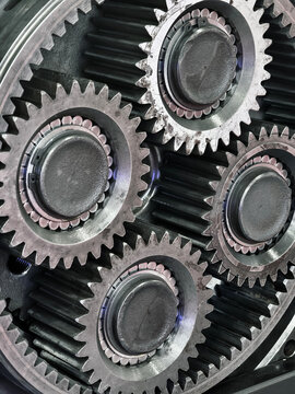 Close view of four metal gears in a mechanical system showing details of teeth and bearings during assembly process in a workshop