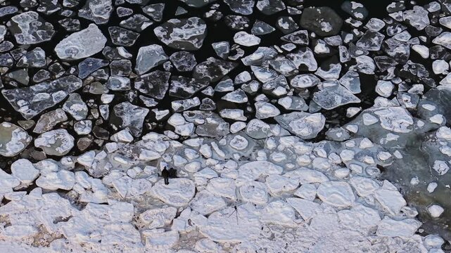 Aerial view of the Baltic sea showing a stark contrast between the dark water and the bright white ice floes, Sopot, pomorskie, Poland.